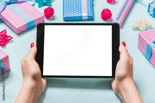 Cuadros en Lienzo Top view of woman holding tablet in her hands on blue background made of Christmas decorations