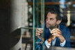 © mavoimages - Young businessman sitting by a window inside of a cafe