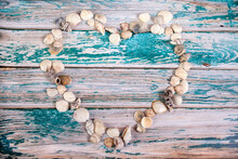 Seashells Laid Out In The Shape Of A Heart On A Blue Wooden Background. Copy Spaes.