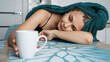 © brillianata - Tired woman sleeping on the table. Beautiful woman in a towel on hair. Hand reaches for the mug. Lazy sleepy morning