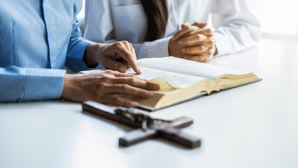 Wall Mural - Christian woman praying with hands together on holy bible and wooden cross. Woman pray for god blessing to wishing have a better life and believe in goodness.