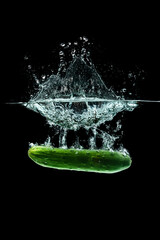 Cucumber splashing water isolated onblack background. Healthy food.