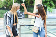 © dzmatph - two young female friends meeting in the street and greeting each other with elbows