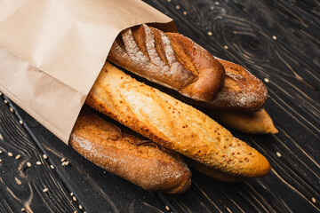 Wall Mural - fresh baked baguette loaves in paper bag on wooden surface