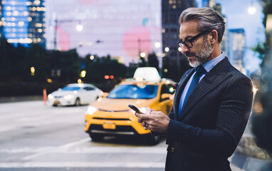 Wall Mural - Mature businessman using smartphone against New York road