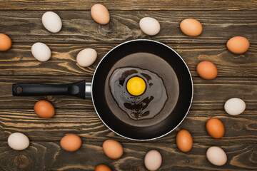 Wall Mural - top view of fresh chicken eggs and frying pan on wooden surface