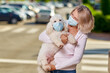 © JENOCHE - Funny woman with dog in antivirus mask on the street.
