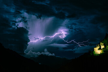 Wall Mural - bolt of lightning cuts through the sky near a castle in the mountains