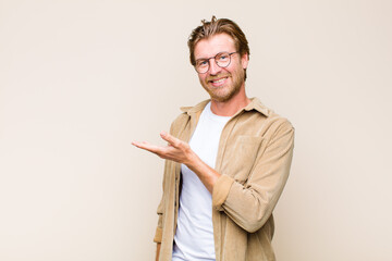 Wall Mural - blonde adult caucasic man smiling cheerfully, feeling happy and showing a concept in copy space with palm of hand