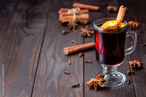 Fotografía Red glogg or mulled wine with orange slices and cinnamon stick on dark wooden ba