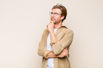 Wall Mural - blonde adult caucasic man feeling thoughtful, wondering or imagining ideas, daydreaming and looking up to copy space