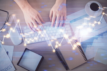 Multi exposure of man's hands typing over computer keyboard and forex graph hologram drawing. Top view. Financial markets concept.