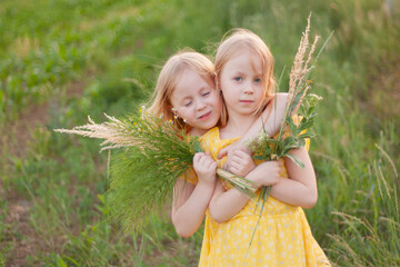 close-up portrait of two preschool girls in yellow dresses in nature,