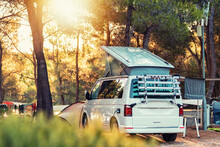 Campervan Caravan Vehicle For Van Life Holiday On Mobile Home Camper Mobile Motor Home. Golden Sunshine Sneaking Through Sparse Trees Of Camping. Roof Of Campervan Is Covered In Colourful Sunshine