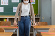© JR-50 - An Asian teacher uses a tape measure to measure the distance of the student's desk to keep student's social distance in the classroom, preventing the coronavirus outbreak.