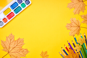 Wall Mural - education and stationery concept. above view for yellow desk. decorated fall leaves and color pencils, markers and other tools. empty space for design