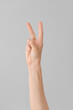© Pixel-Shot - Hand showing letter K on grey background. Sign language alphabet
