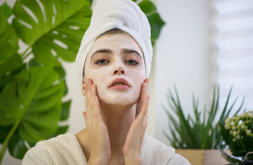 Young woman applying face mask on her face.