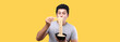  Close up Asian man eating yummy hot and spicy instant noodle using chopsticks and bowl isolated on yellow background in studio With copy space.