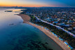 Aerial sunset view of Brighton beach, with St Kilda Marina and the city of Melbourne in the distance, captured at dusk