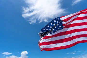 Waving USA flag under blue sky background.