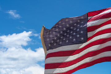 Waving USA flag under blue sky background.