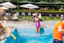 Selective Focus Of Girl Shooting From Water Gun While Having Fun With Friends Near Pool