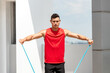 © Atstock Productions - Handsome sports man doing shoulder lateral raise exercise with resistance band outdoors on rooftop in the sun