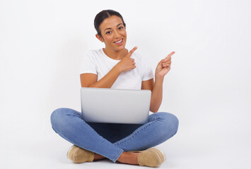 Wall Mural - Advertisement concept. Positive, pretty, caucasion woman with beaming smile in jeans shirt on grey background is pointing with her two index finger and looking on empty copy space.