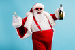 © deagreez - Photo of retired old man grey beard funky hold bottle full glass golden wine drink having fun open mouth wear santa x-mas costume suspender sunglass cap isolated blue color background