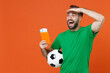 Excited man football fan in green t-shirt cheer up support favorite team with soccer ball hold passport ticket looking far away distance isolated on orange background. People sport leisure concept.