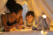 © Rido - Mother and daughter playing at home in tent