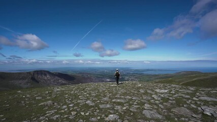 Wall Mural - Mountain hiker walking a summit in the Welsh mountains of Snowdonia UK