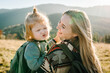 © Serhii - Mother with kid hiking in autumn mountains. Young tourists on top of a mountain enjoying sunset. Happy family. Mom with backpack hugging daughter. Holiday trip concept. World Tourism Day. Back view.