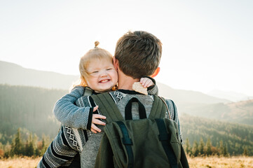 father and child with a backpack enjoying the sunset in the mountains.the concept of family travel, 