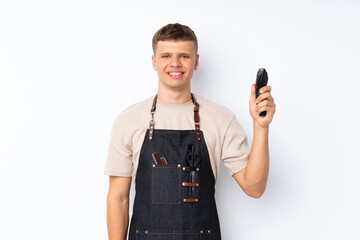 Wall Mural - Young handsome man over isolated white background with hairdresser or barber dress and holding hair cutting machine