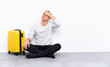 © luismolinero - Young handsome man sitting on the floor with a suitcase laughing