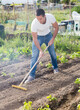 © JackF - Young man gardener with rake working at land in garden outdoor