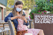 Young woman in town using smartphone, wearing face mask during 2019-ncov