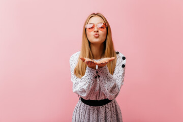 Wall Mural - Glad young lady sending air kiss during studio photoshoot. Glamorous caucasian girl in casual blouse expressing love.