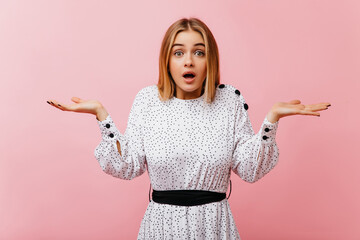 Wall Mural - Surprised white lady in elegant dress posing on rosy background. Debonair shapely girl expressing amazement in studio.