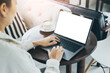 © panitan - computer mockup blank screen.hand woman work using laptop with white background for advertising,contact business search information on desk at coffee shop.marketing and creative design
