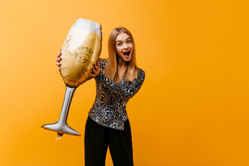 Wall Mural - Girl in trendy clothes fooling around at birthday party. Photo of smiling beautiful woman with giant wineglass.