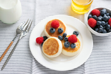 Wall Mural - Curd cheese fritters with summer berries and honey served on white porcelain plate. Healthy sweet breakfast food