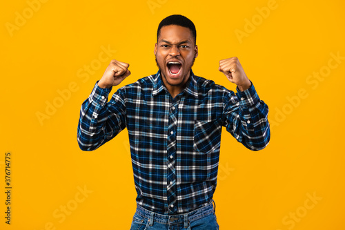 Photographie Emotional African Man Shouting Loudly Shaking Fists Over Yellow Background
