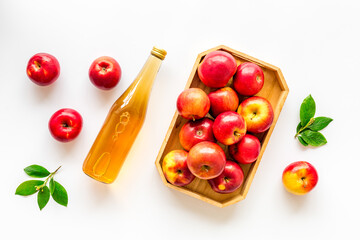 Apple cider vinegar in glass bottle and wooden tray with red apples