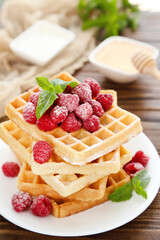 Poster - Tasty waffles with fresh raspberries and mint leafs on brown wooden background