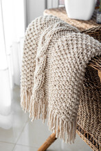 Detail Of Hand-woven Beige Wool Blanket On Wicker Chair.
