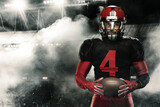 Fototapeta Sport - American football player, athlete sportsman in red helmet on stadium background. Sport and motivation wallpaper.