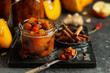 Homemade pumpkin and apple chutney with raisins in jars on a table. Delicious sweet spicy sauce preserved for autumn and winter season.
